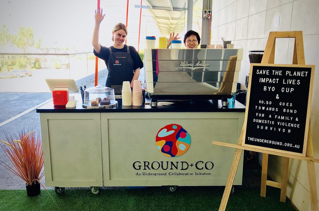Image of two baristas waving behind the Ground+Co coffee cart at Brookfield place